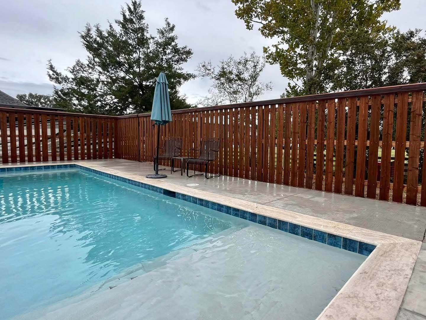 Semi privacy wood fence with beveled edge top cap trim installed around a swimming pool